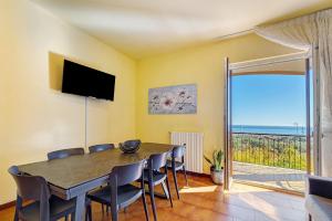 a dining room with a table and chairs and a balcony at Villa Cristina - vista mare in Boissano