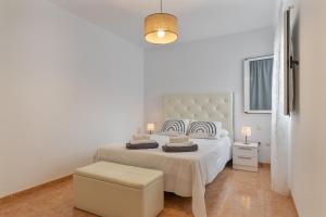 a white bedroom with a large white bed and a lamp at El Barquillo in La Santa
