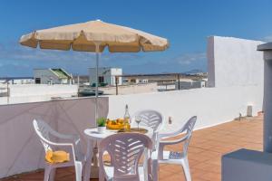 a table and chairs with an umbrella on a roof at El Barquillo in La Santa