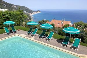 a group of chairs and umbrellas next to a swimming pool at Agriturismo La Realidad in Finale Ligure