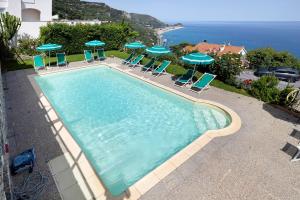a large swimming pool with chairs and umbrellas at Agriturismo La Realidad in Finale Ligure