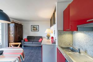 a kitchen with red cabinets and a couch in a room at Entre Terre et Mer in Ciboure
