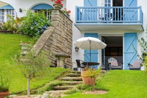 a house with a table and an umbrella in the yard at Entre Terre et Mer in Ciboure