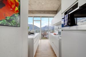 a kitchen with white counters and a large window at Villa Alvarium Eins in Schenna
