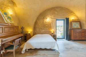 a bedroom with a bed and a piano at L'Amaryflor in Vaugines