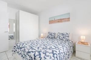 a white bedroom with a bed and two lamps at Vistamar in Puerto del Carmen