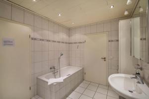 a white bathroom with a tub and a sink at mit Wintergarten nah Moviepark in Bottrop +13 photos