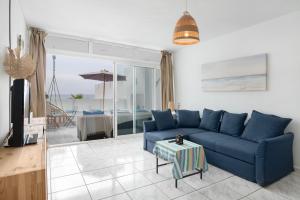 a living room with a blue couch and a view of the ocean at Vistamar in Puerto del Carmen