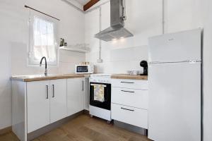 a kitchen with white cabinets and a white refrigerator at Ca Lajares in Lajares +16 photos