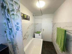 a bathroom with a white tub and a green towel at Ferienwohnungen Neuseenland in Rötha +29 photos