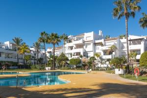 a resort with a swimming pool and palm trees at Apartamento de lujo a 30m playa in Estepona