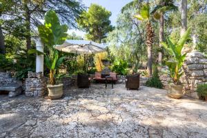 a patio with an umbrella and chairs and trees at Villa Massa depandance in Polignano a Mare