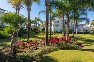 a park with palm trees and flowers in front of a building at Apartamento de lujo a 30m playa in Estepona