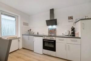 a kitchen with white cabinets and a stove top oven at Fewo Weber in Sankt Ingbert