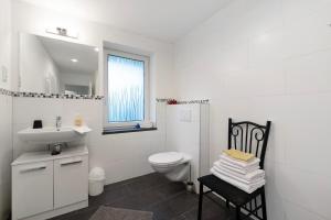 a white bathroom with a toilet and a sink at Fewo Weber in Sankt Ingbert +15 photos