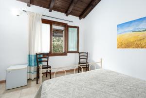 a bedroom with a bed and two chairs at Su Birde Agriturismo in Orosei