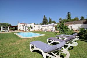 a group of lounge chairs sitting next to a pool at Villa Carmen in Ronda