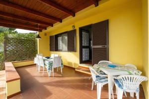 a patio with white chairs and a table on a yellow wall at Casa Luisella in Costa Rei