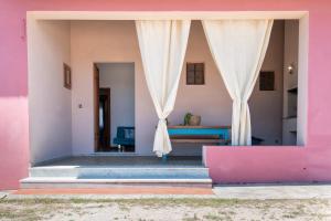 a pink house with curtains in the doorway at Spacious home in Costa Rossa in Trinità d'Agultu e Vignola