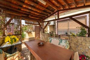 a patio with a wooden table and a stone wall at Monolocale Il Girasole in Villaputzu
