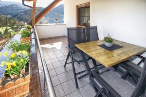 a balcony with a wooden table and chairs at Trenklehof in Simonswald