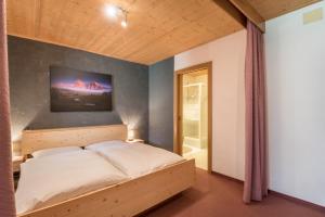 a bedroom with a bed and a wall with a tv at Sabina Dolomites Euringer in Alpe di Siusi