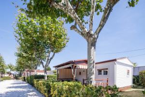 a white house with a tree next to a sidewalk at Bungalow B1 in Pontevedra
