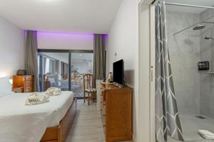 a hotel room with a bed and a shower at Paraiso Madeira - Suites in Gaula