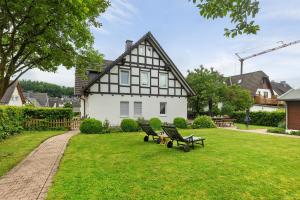 a house with benches in the grass in front of it at Ferienwohnung Blumenau in Schmallenberg