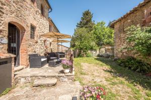 a patio with chairs and an umbrella and flowers at Casale Rosennano - Loggia in Rosennano