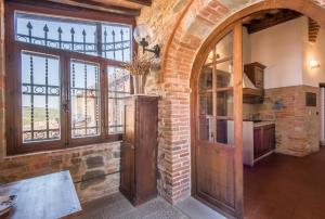a kitchen with a brick wall and a wooden door at Casale Rosennano - Loggia in Rosennano