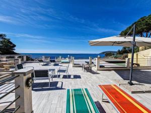 a deck with chairs and an umbrella and the ocean at Villa Galatea Stella Marina in Capoliveri