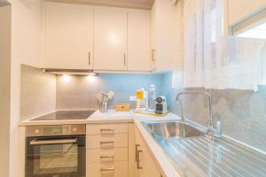 a kitchen with white cabinets and a sink at Seawind Gouvia in Corfu +12 photos