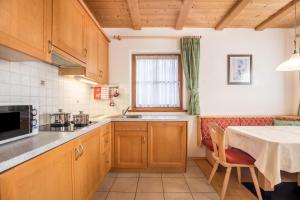 a kitchen with wooden cabinets and a table and a window at App Lisüra Boè in Corvara in Badia