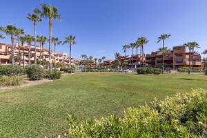 a park with palm trees and buildings in the background at Exclusive frontline beach penthouse in Estepona