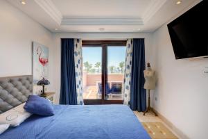 a bedroom with a blue bed and a window at Exclusive frontline beach penthouse in Estepona +23 photos