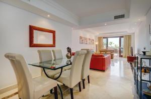a dining room with a glass table and white chairs at Exclusive frontline beach penthouse in Estepona