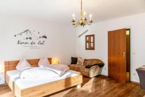 a bedroom with a bed and a couch and a chandelier at Aschaubichl - Wohnung Bergaurikel in Grainau