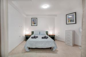 a white bedroom with a bed and two night stands at Las Flores 1D in Costa de Adeje