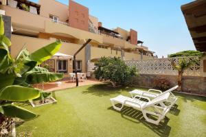 a yard with two white chairs and a building at Casa Carlos in Corralejo