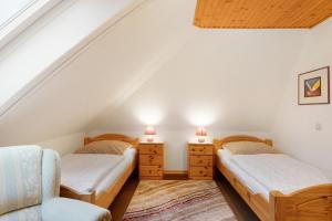 two twin beds in a attic room with two chairs at Ferienwohnung Offenbüttel in Oldenbüttel