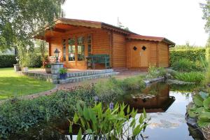 a log cabin with a pond in front of it at Ferienwohnung Offenbüttel in Oldenbüttel
