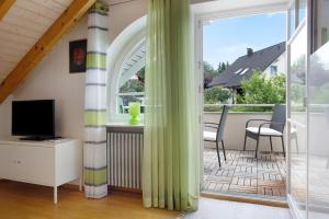 a living room with a television and a balcony at Wohlfühlplatz in Ostrach