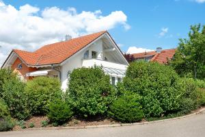 a white house with a red roof and some bushes at Wohlfühlplatz in Ostrach