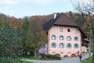 a woman walking past a large pink house at Ziegelhof in Schuttertal