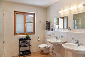 a bathroom with two sinks and a toilet and a mirror at Alpblick Apartment Alpspitze in Garmisch-Partenkirchen +20 photos