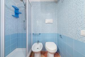 a blue tiled bathroom with a toilet and a shower at Accu is Prezzus E special 50m mare in Villasimius +20 photos