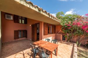 a patio with a wooden table and chairs in front of a house at Accu is Prezzus E special 50m mare in Villasimius