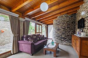 a living room with a purple couch and a stone wall at O Pozo in Ordes