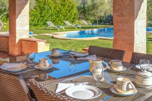 an outdoor table with plates and wine glasses next to a pool at Can Vaja in Pollença
